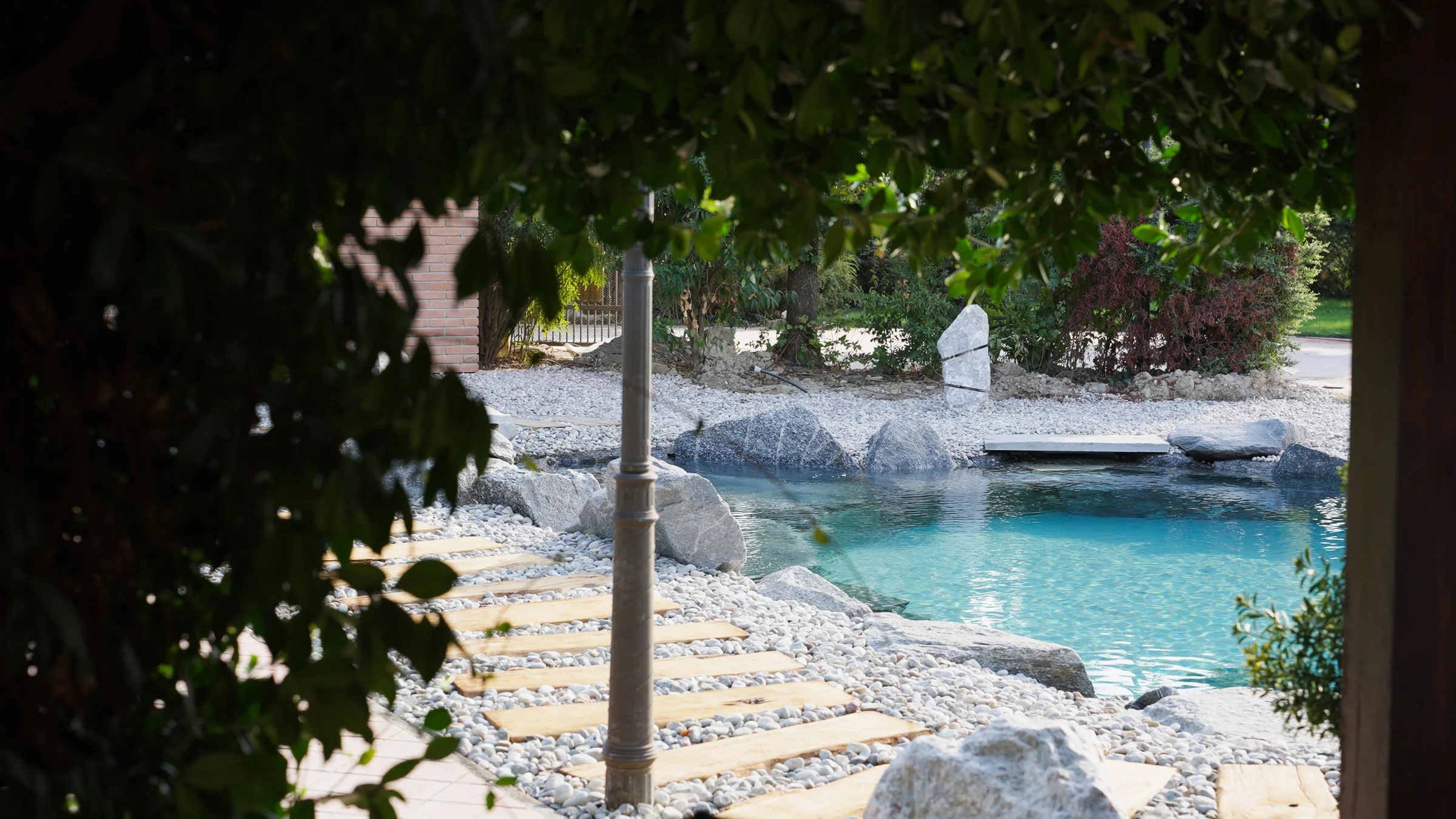 Piscina naturale vista tra gli alberi del giardino