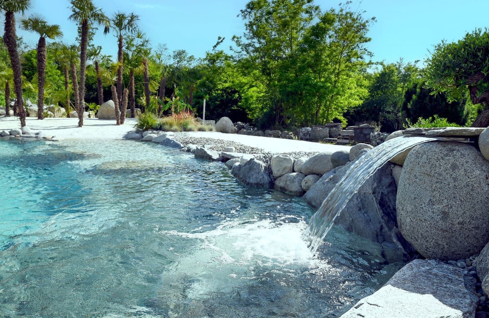 Piscina naturale con effetto spiaggia e cascata